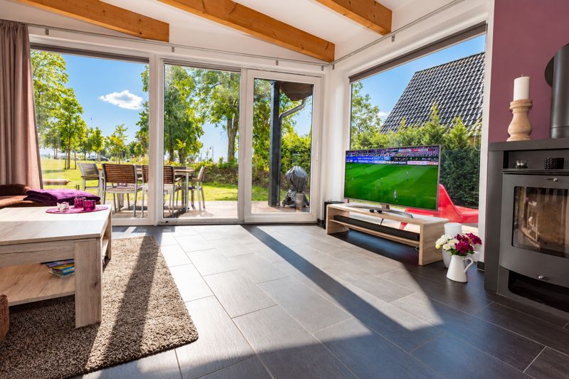 Wohnbereich von Thea mit lila Wand, Kaminofen und großen Fenstern zur Terrasse
